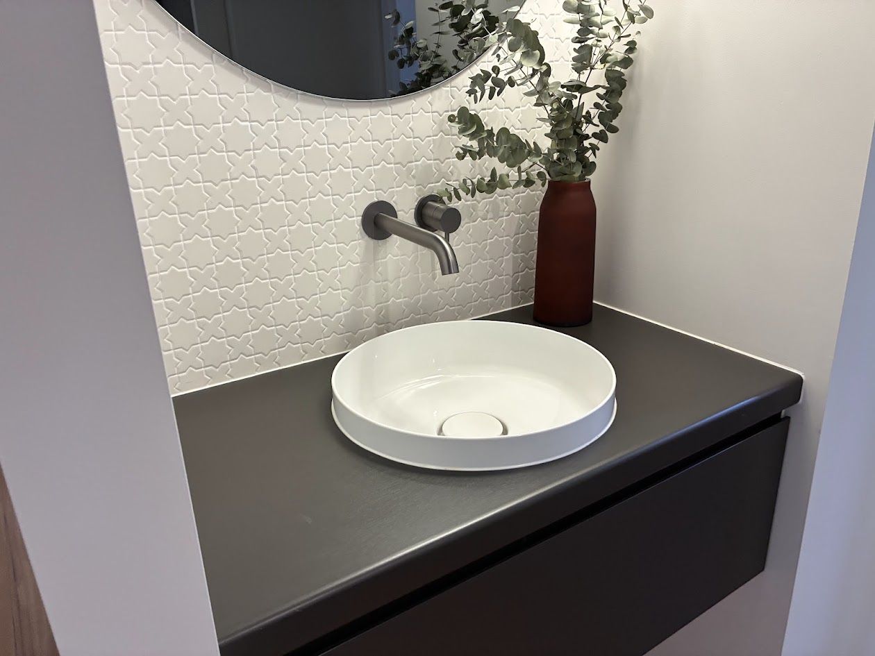 Round basin on a charcoal floating vanity with patterned white tiles